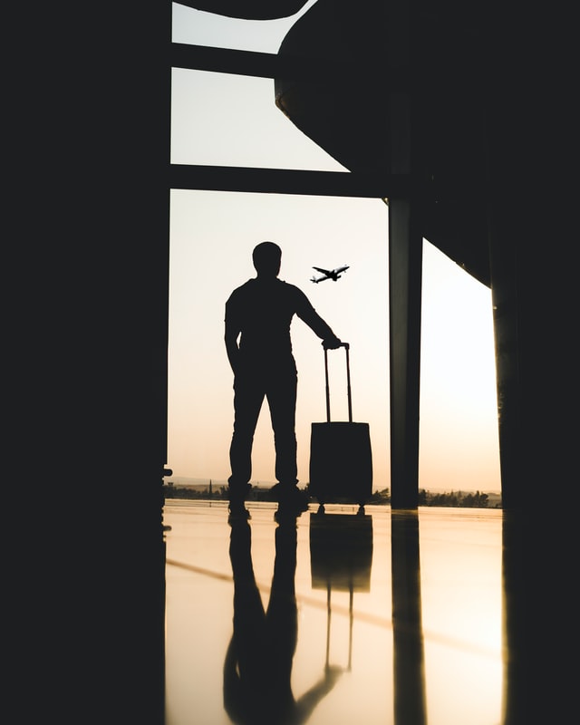 person standing alone at airport with luggage